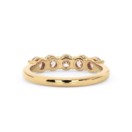 A picture of a five stone diamond wedding ring with round diamonds that are shared prong set in yellow gold on a white background with a view of the underside of the ring.