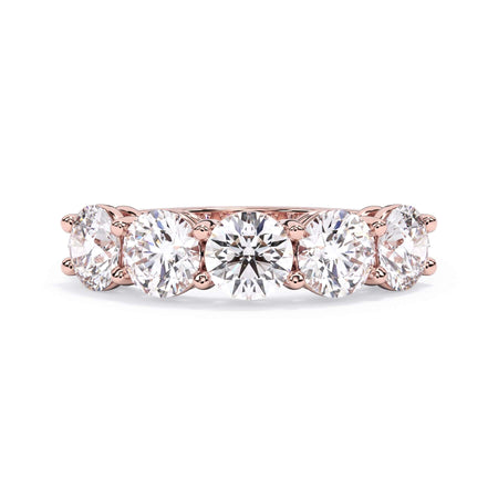 A picture of a five stone diamond wedding ring with round diamonds that are shared prong set in rose gold on a white background with the ring facing forward, lying down.