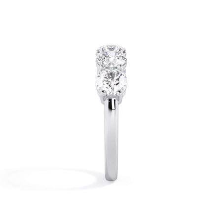 A picture of a five stone diamond wedding ring with round diamonds that are shared prong set in white gold or platinum on a white background with a side profile view.