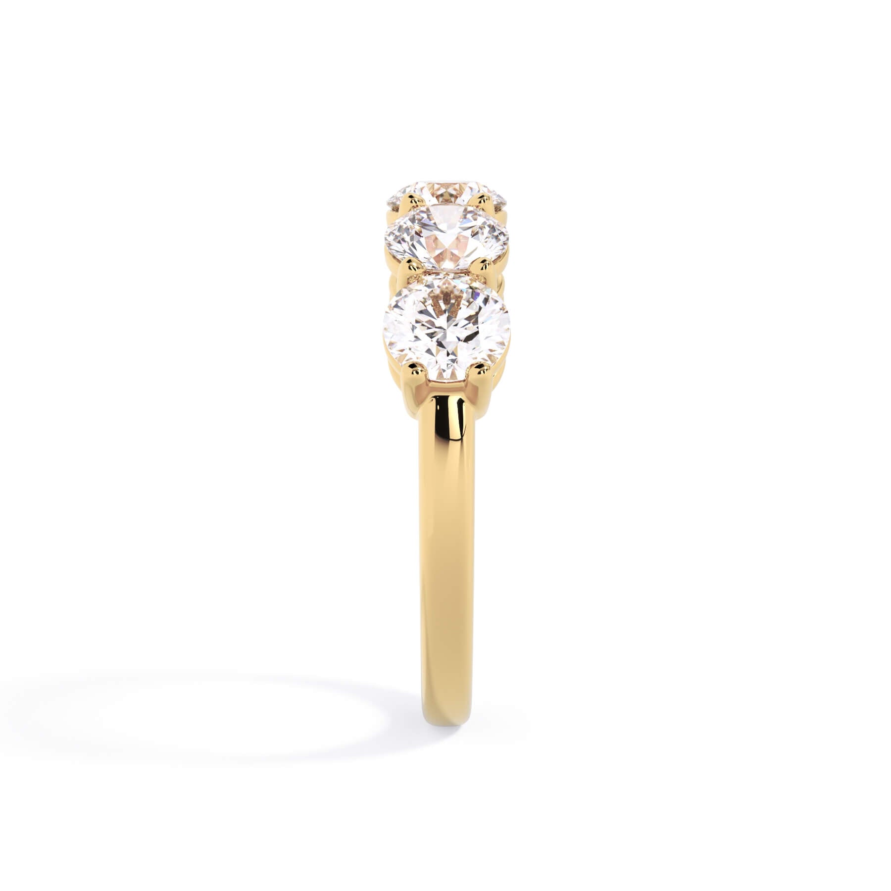 A picture of a five stone diamond wedding ring with round diamonds that are shared prong set in yellow gold on a white background with a side profile view.