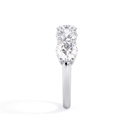 A picture of a five stone diamond wedding ring with round diamonds that are shared prong set in white gold or platinum on a white background with a side profile view.