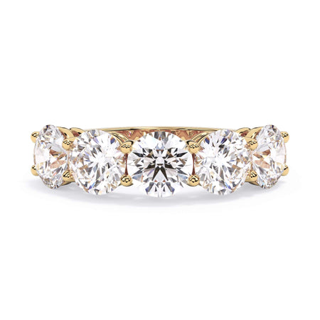 A picture of a five stone diamond wedding ring with round diamonds that are shared prong set in yellow gold on a white background with the ring facing forward, lying down.