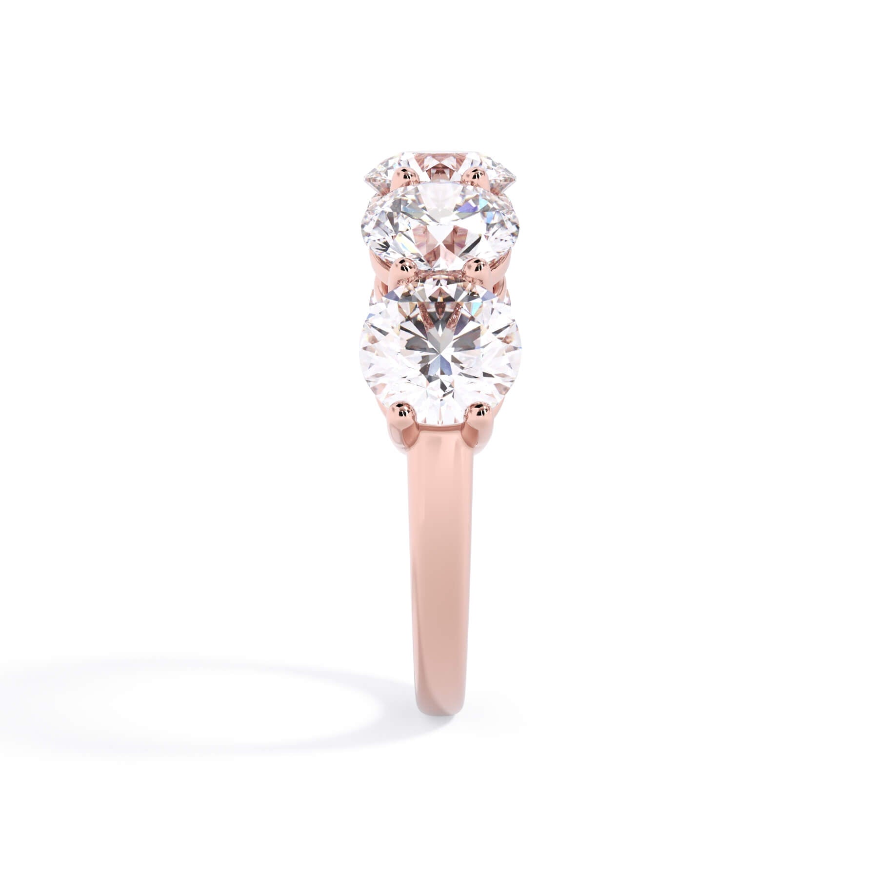 A picture of a five stone diamond wedding ring with round diamonds that are shared prong set in rose gold on a white background with a side profile view.
