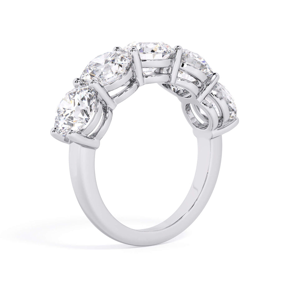 A picture of a five stone diamond wedding ring with round diamonds that are shared prong set in white gold or platinum on a white background with a slightly angled, through the finger view.