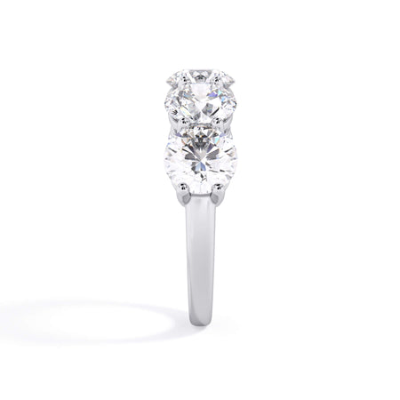 A picture of a five stone diamond wedding ring with round diamonds that are shared prong set in white gold or platinum on a white background with a side profile view.
