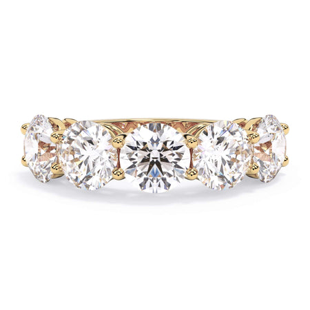 A picture of a five stone diamond wedding ring with round diamonds that are shared prong set in yellow gold on a white background with the ring facing forward, lying down.