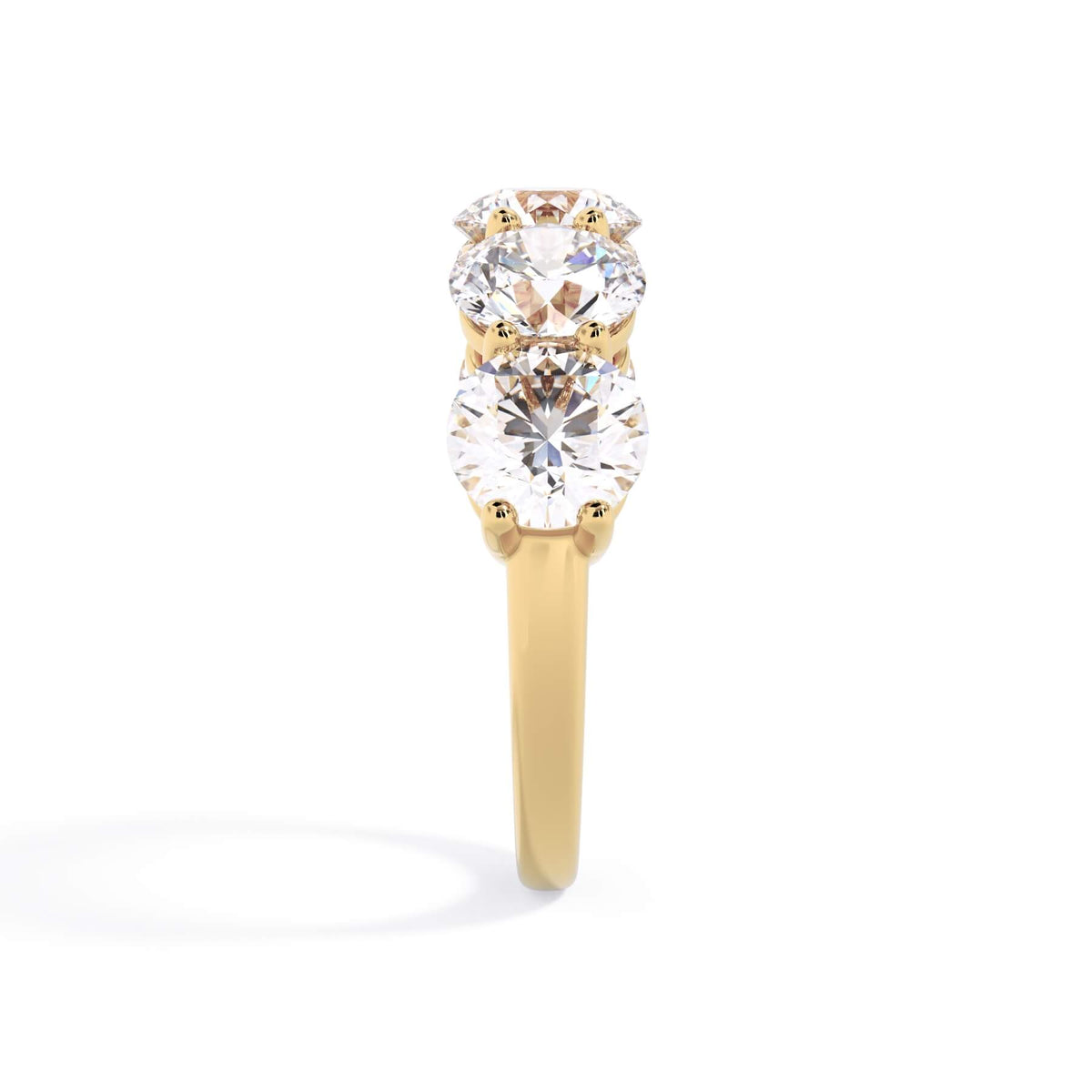 A picture of a five stone diamond wedding ring with round diamonds that are shared prong set in yellow gold on a white background with a side profile view.