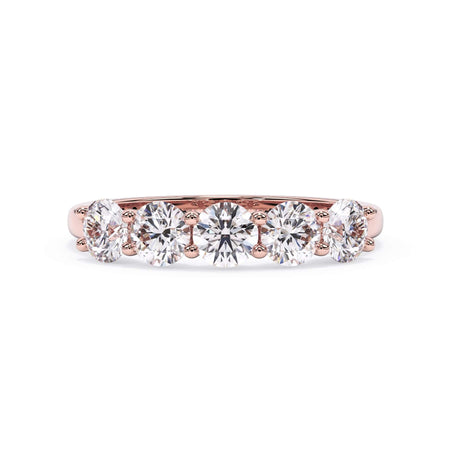 A picture of a five stone diamond wedding ring with round diamonds that are u prong set in rose gold on a white background with the ring facing forward, lying down.