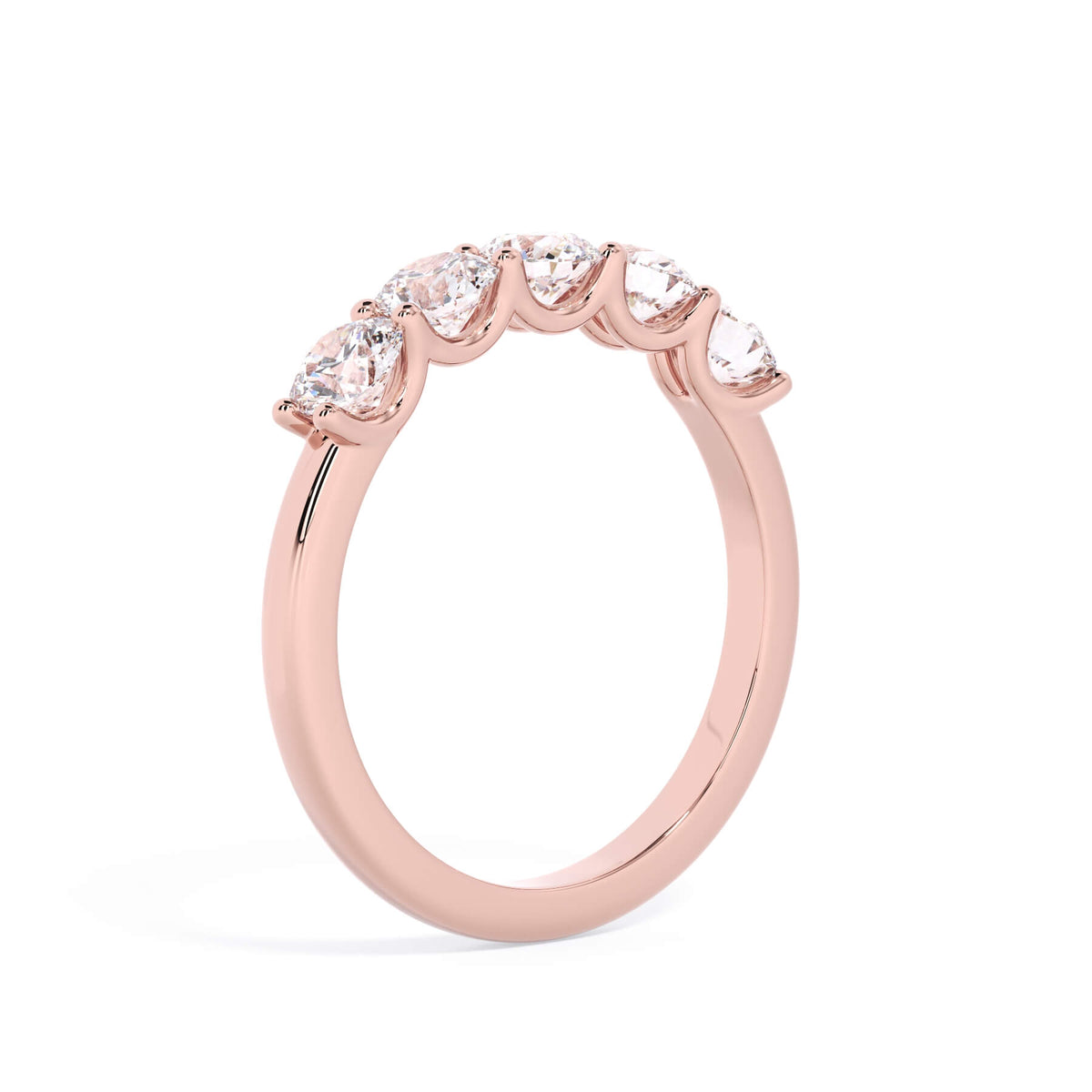 A picture of a five stone diamond wedding ring with round diamonds that are u prong set in rose gold on a white background with a slightly angled, through the finger view.