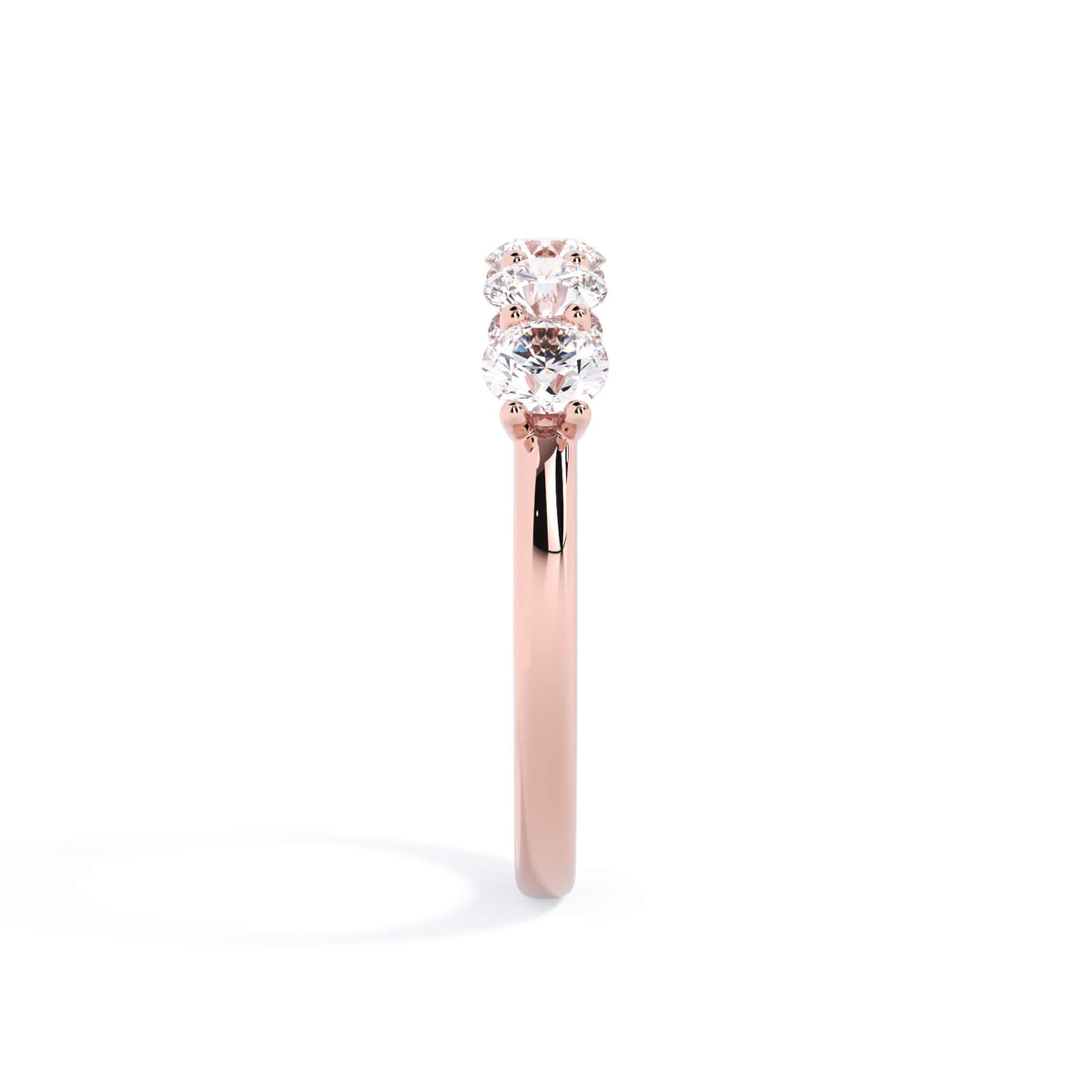 A picture of a five stone diamond wedding ring with round diamonds that are u prong set in rose gold on a white background with a side profile view.