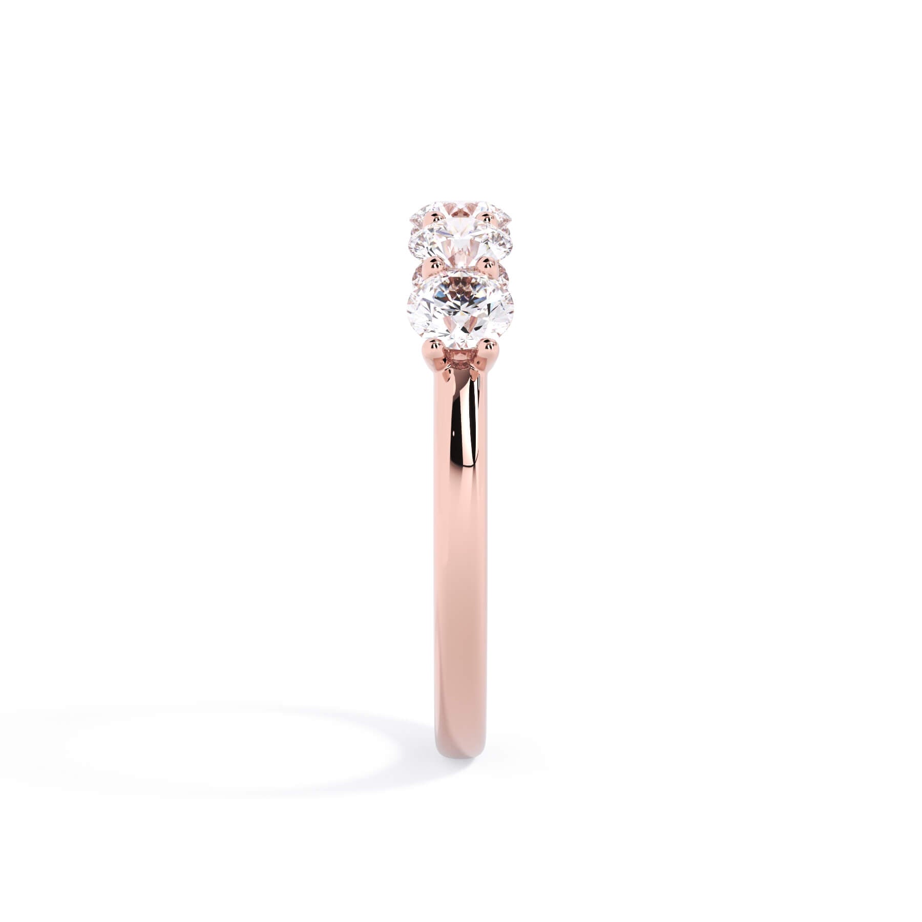 A picture of a five stone diamond wedding ring with round diamonds that are u prong set in rose gold on a white background with a side profile view.