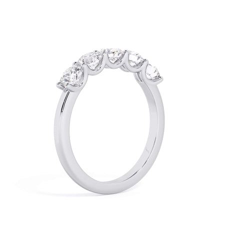 A picture of a five stone diamond wedding ring with round diamonds that are u prong set in white gold or platinum on a white background with a slightly angled, through the finger view.