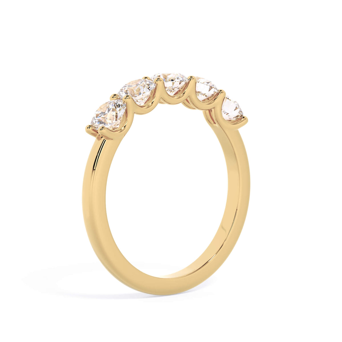 A picture of a five stone diamond wedding ring with round diamonds that are u prong set in yellow gold on a white background with a slightly angled, through the finger view.
