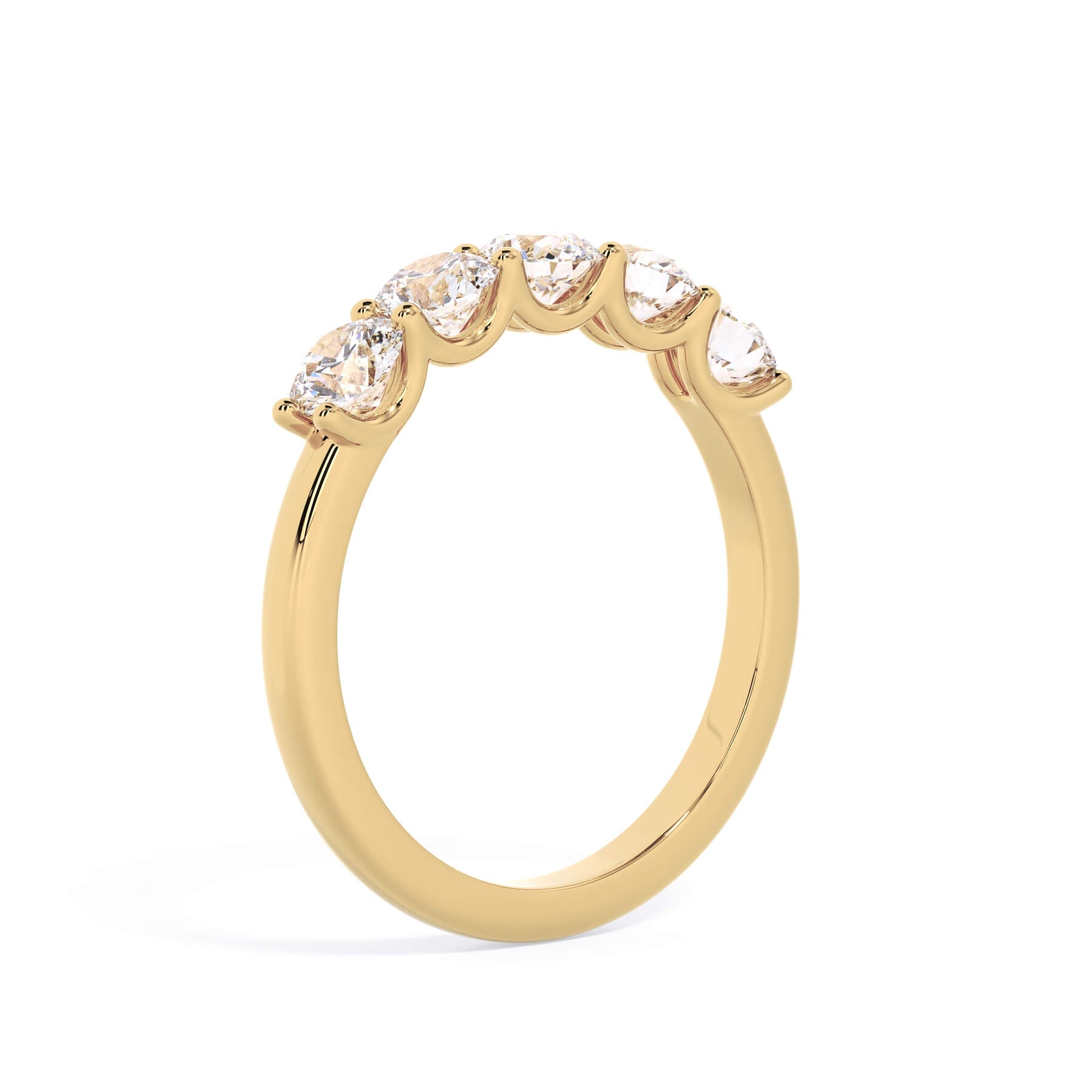 A picture of a five stone diamond wedding ring with round diamonds that are u prong set in yellow gold on a white background with a slightly angled, through the finger view.