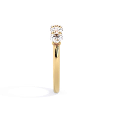A picture of a five stone diamond wedding ring with round diamonds that are u prong set in yellow gold on a white background with a side profile view.