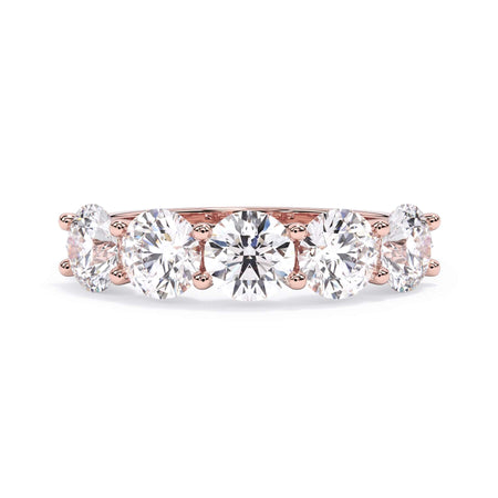 A picture of a five stone diamond wedding ring with round diamonds that are u prong set in rose gold on a white background with the ring facing forward, lying down.