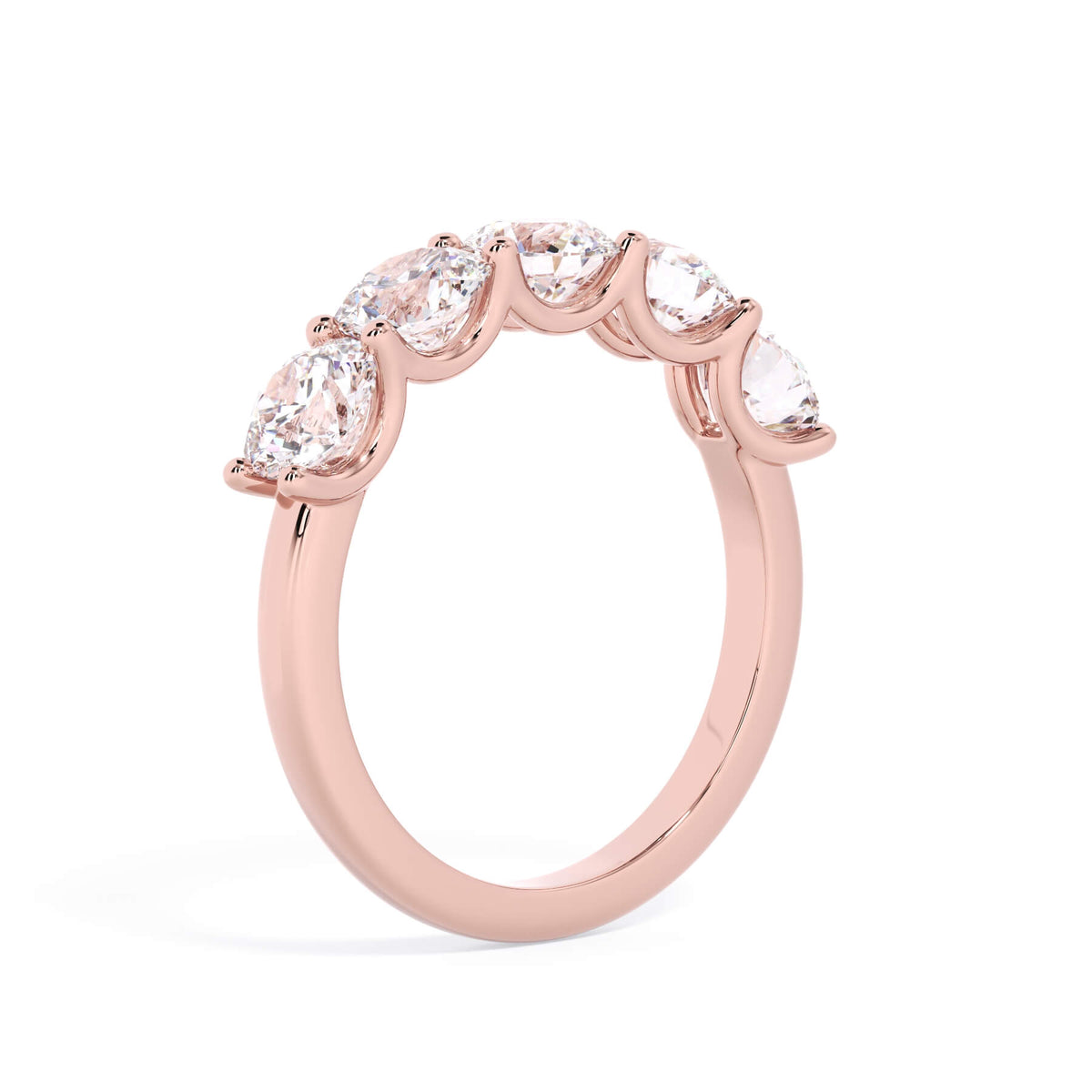 A picture of a five stone diamond wedding ring with round diamonds that are u prong set in rose gold on a white background with a slightly angled, through the finger view.