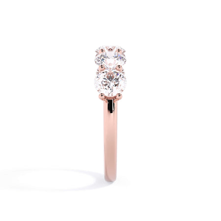 A picture of a five stone diamond wedding ring with round diamonds that are u prong set in rose gold on a white background with a side profile view.