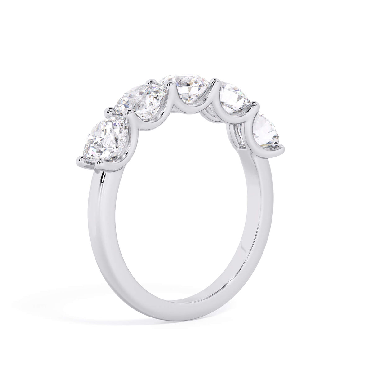 A picture of a five stone diamond wedding ring with round diamonds that are u prong set in white gold or platinum on a white background with a slightly angled, through the finger view.