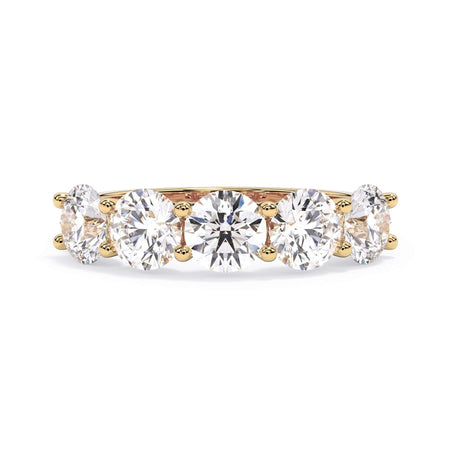 A picture of a five stone diamond wedding ring with round diamonds that are u prong set in yellow gold on a white background with the ring facing forward, lying down.