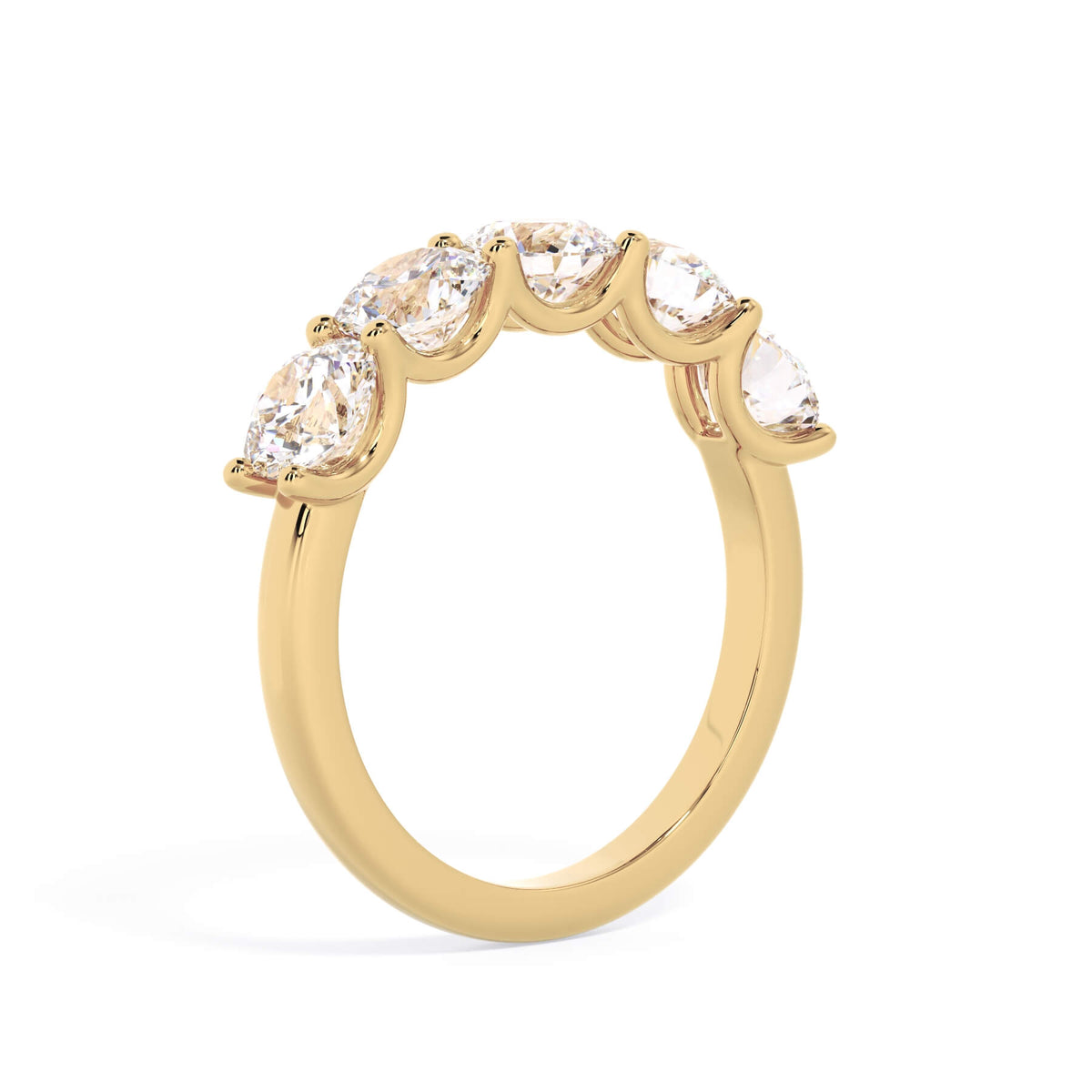 A picture of a five stone diamond wedding ring with round diamonds that are u prong set in yellow gold on a white background with a slightly angled, through the finger view.