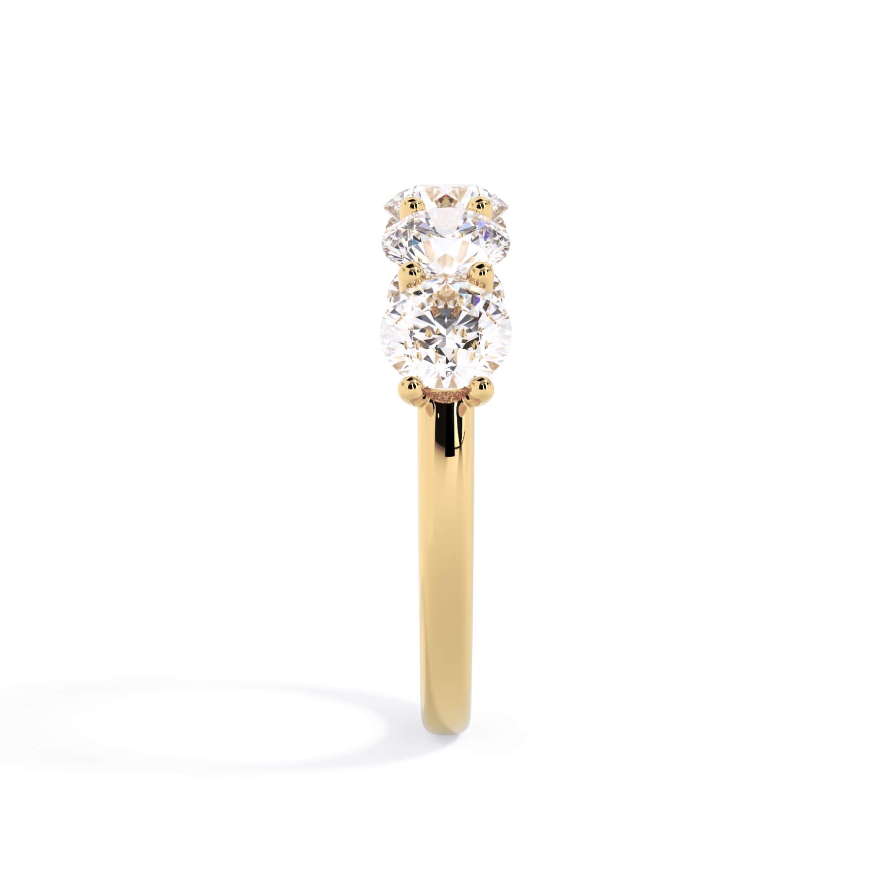 A picture of a five stone diamond wedding ring with round diamonds that are u prong set in yellow gold on a white background with a side profile view.