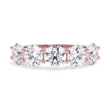 A picture of a five stone diamond wedding ring with round diamonds that are u prong set in rose gold on a white background with the ring facing forward, lying down.