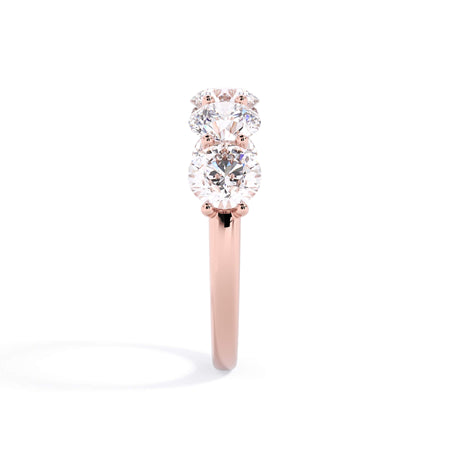 A picture of a five stone diamond wedding ring with round diamonds that are u prong set in rose gold on a white background with a side profile view.
