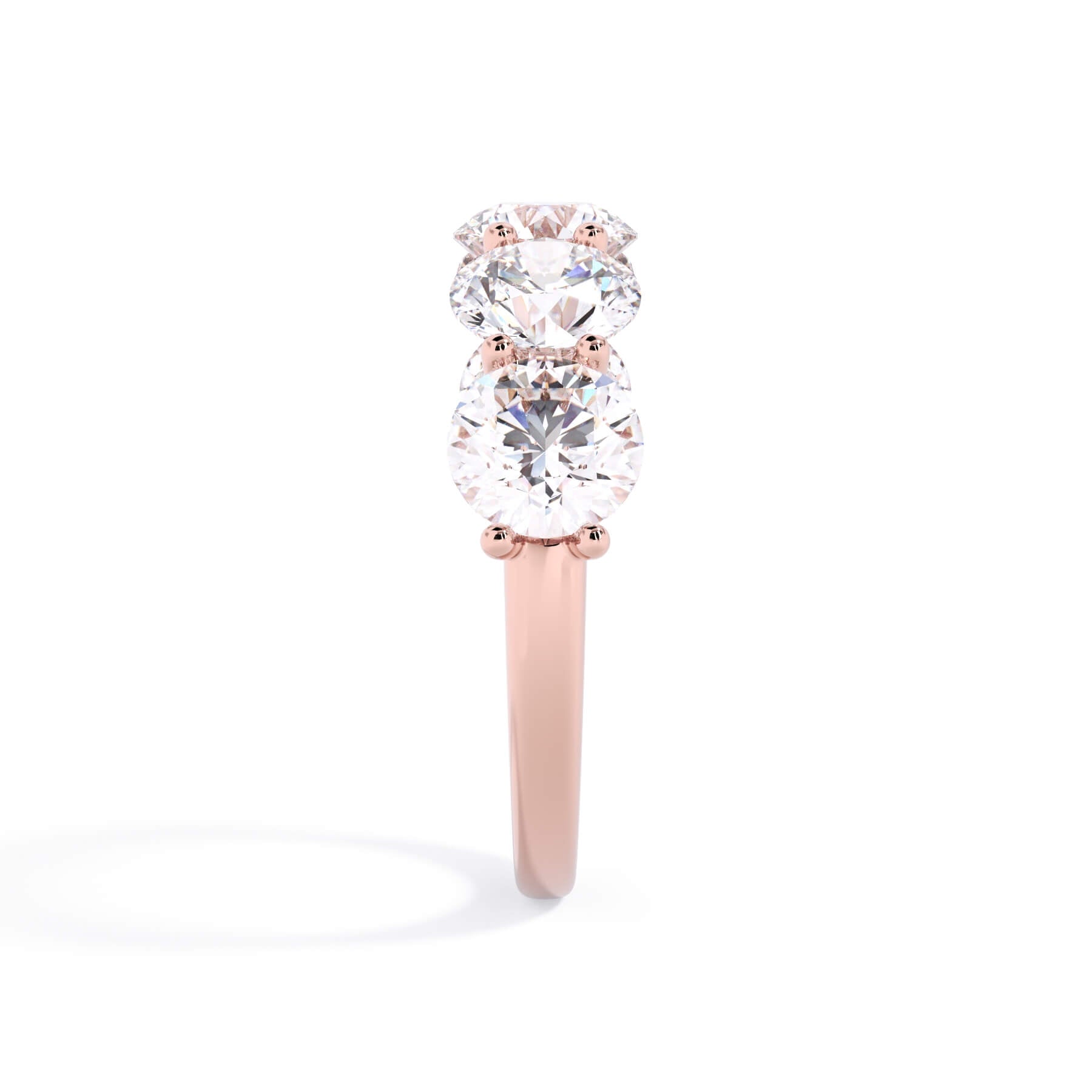A picture of a five stone diamond wedding ring with round diamonds that are u prong set in rose gold on a white background with a side profile view.