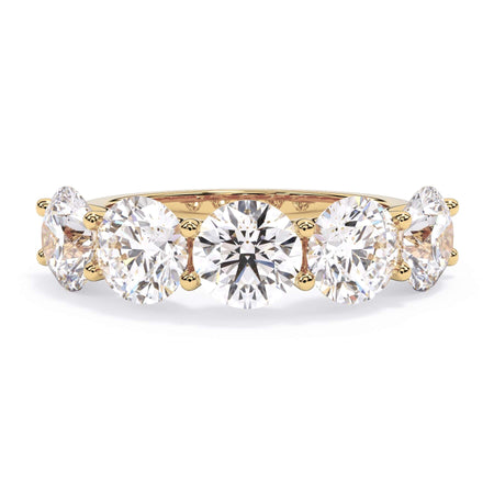 A picture of a five stone diamond wedding ring with round diamonds that are u prong set in yellow gold on a white background with the ring facing forward, lying down.