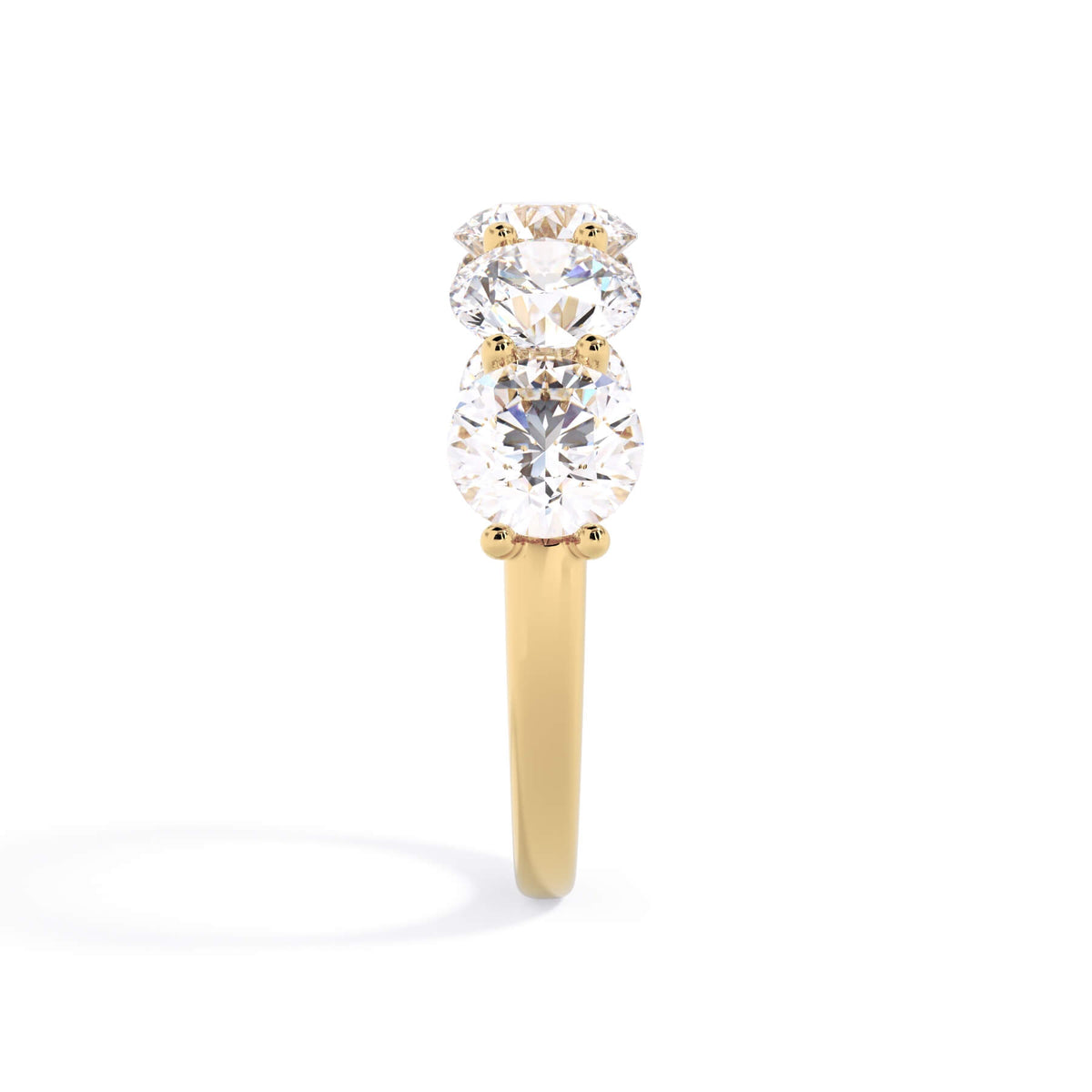 A picture of a five stone diamond wedding ring with round diamonds that are u prong set in yellow gold on a white background with a side profile view.