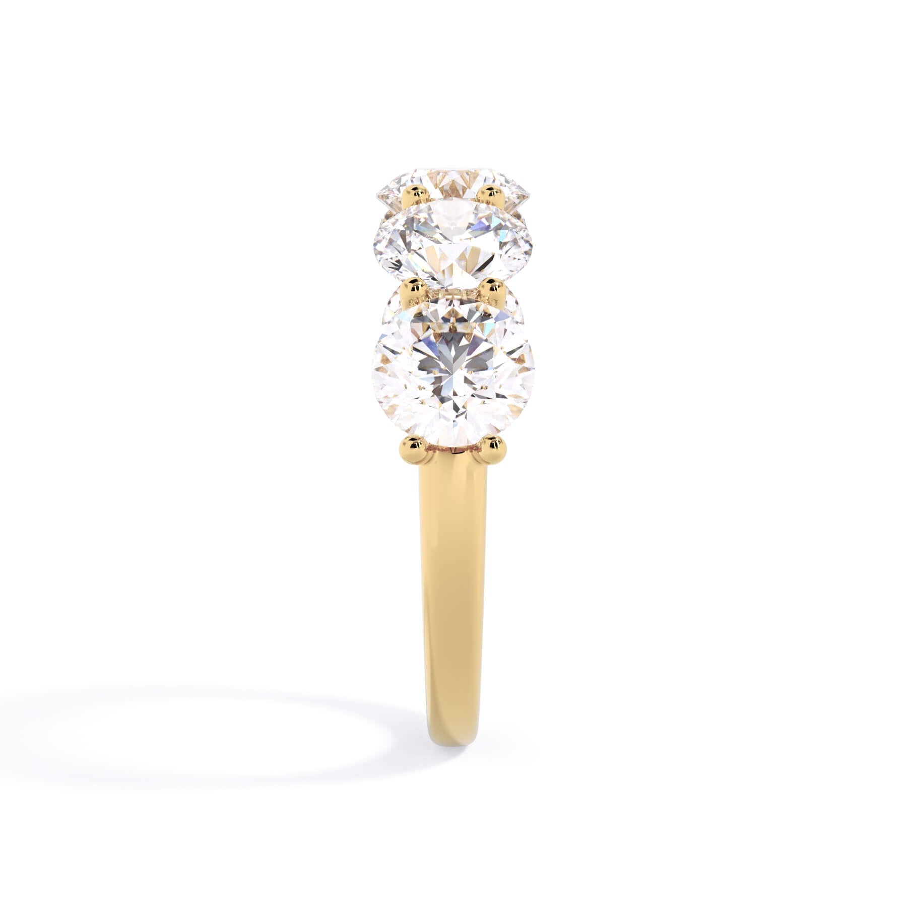 A picture of a five stone diamond wedding ring with round diamonds that are u prong set in yellow gold on a white background with a side profile view.