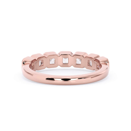 A picture of a seven stone diamond wedding ring with asscher cut diamonds that are bezel set in rose gold on a white background with a view of the underside of the ring.