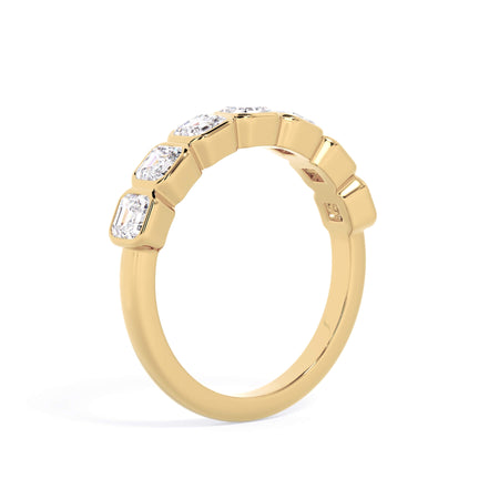 A picture of a seven stone diamond wedding ring with asscher cut diamonds that are bezel set in yellow gold on a white background with a slightly angled, through the finger view.