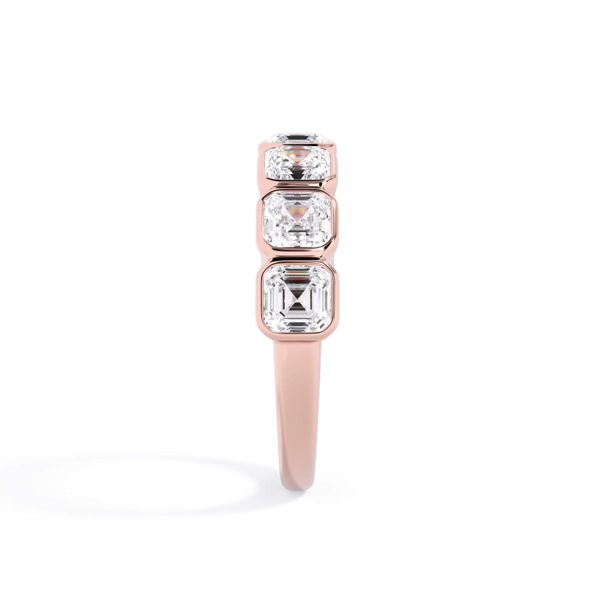 A picture of a seven stone diamond wedding ring with asscher cut diamonds that are bezel set in rose gold on a white background with a side profile view.