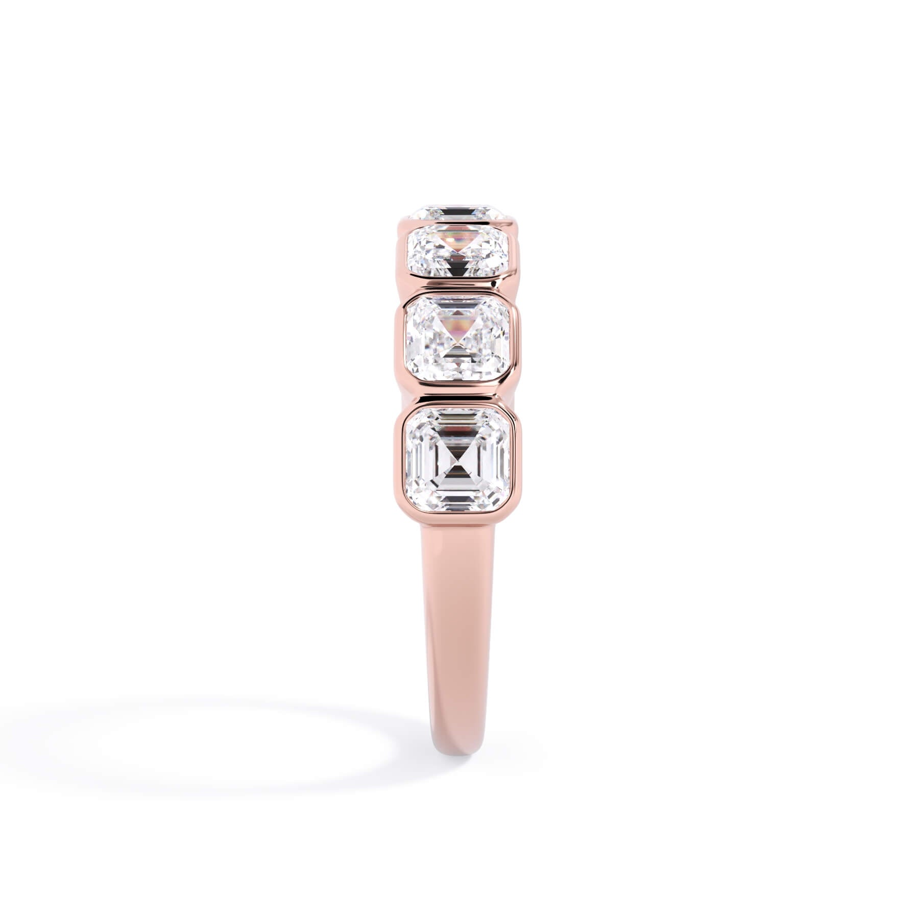 A picture of a seven stone diamond wedding ring with asscher cut diamonds that are bezel set in rose gold on a white background with a side profile view.