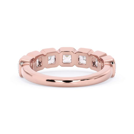 A picture of a seven stone diamond wedding ring with asscher cut diamonds that are bezel set in rose gold on a white background with a view of the underside of the ring.