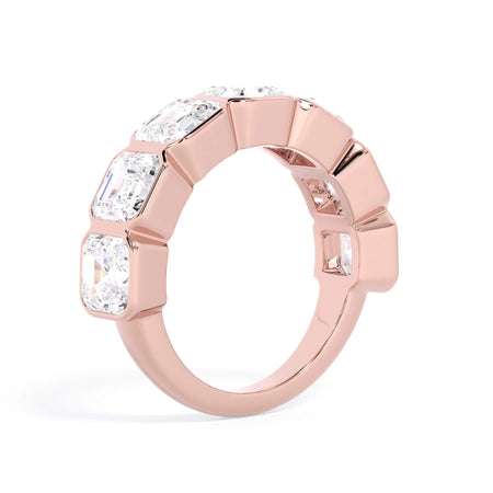 A picture of a seven stone diamond wedding ring with asscher cut diamonds that are bezel set in rose gold on a white background with a slightly angled, through the finger view.