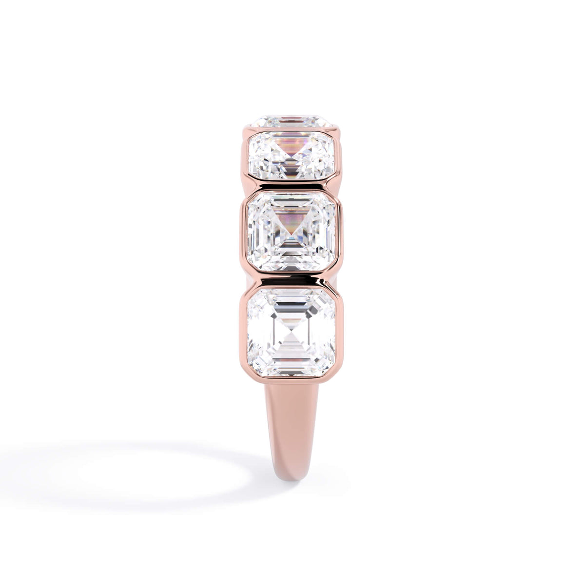 A picture of a seven stone diamond wedding ring with asscher cut diamonds that are bezel set in rose gold on a white background with a side profile view.