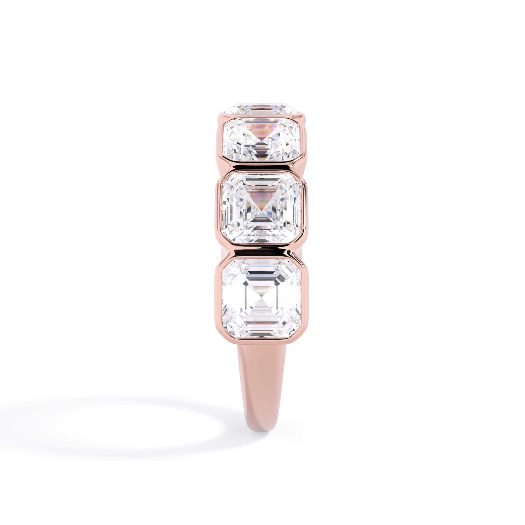 A picture of a seven stone diamond wedding ring with asscher cut diamonds that are bezel set in rose gold on a white background with a side profile view.