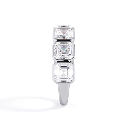 A picture of a seven stone diamond wedding ring with asscher cut diamonds that are bezel set in white gold or platinum on a white background with a side profile view.