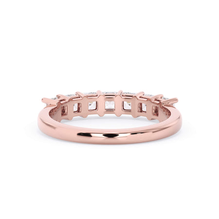 A picture of a seven stone diamond wedding ring with asscher cut diamonds that are shared prong set in rose gold on a white background with a view of the underside of the ring.