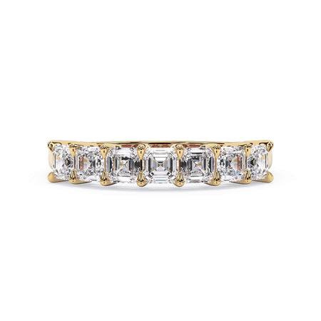 A picture of a seven stone diamond wedding ring with asscher cut diamonds that are shared prong set in yellow gold on a white background with the ring facing forward, lying down.
