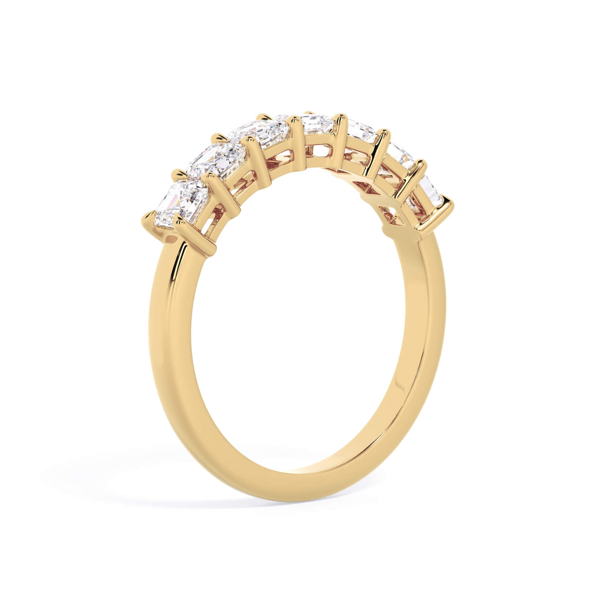 A picture of a seven stone diamond wedding ring with asscher cut diamonds that are shared prong set in yellow gold on a white background with a slightly angled, through the finger view.