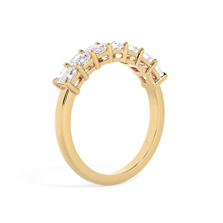 A picture of a seven stone diamond wedding ring with asscher cut diamonds that are shared prong set in yellow gold on a white background with a slightly angled, through the finger view.