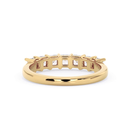 A picture of a seven stone diamond wedding ring with asscher cut diamonds that are shared prong set in yellow gold on a white background with a view of the underside of the ring.