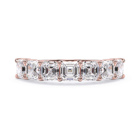 A picture of a seven stone diamond wedding ring with asscher cut diamonds that are shared prong set in rose gold on a white background with the ring facing forward, lying down.