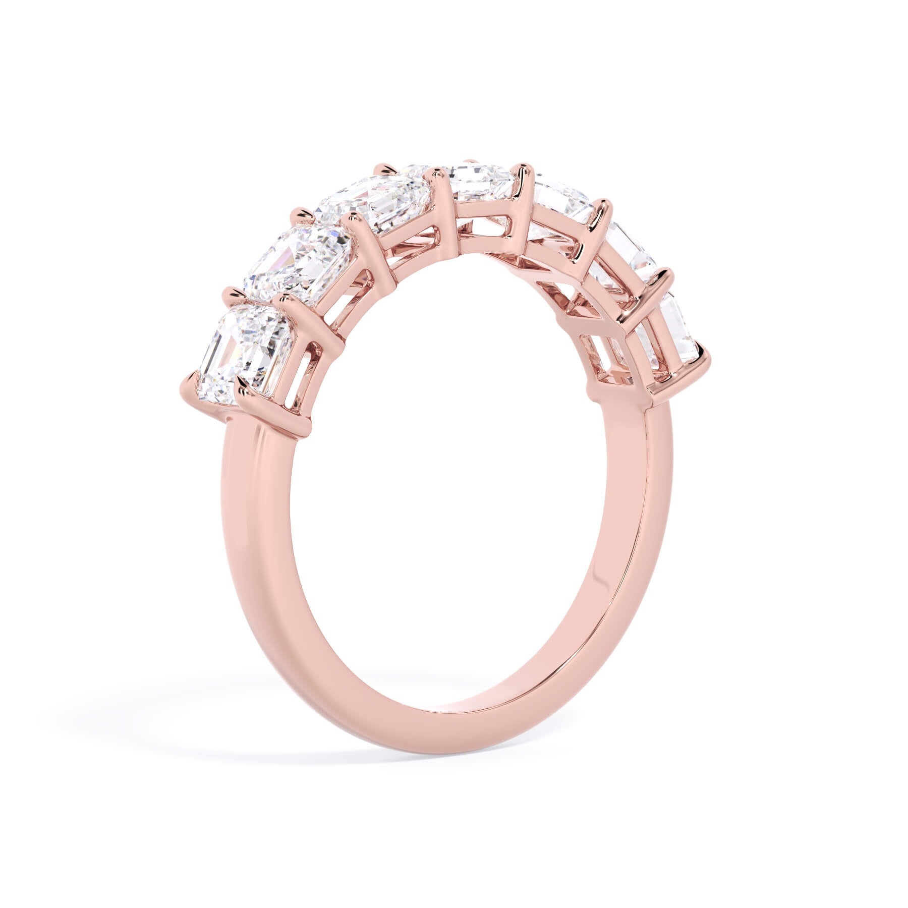 A picture of a seven stone diamond wedding ring with asscher cut diamonds that are shared prong set in rose gold on a white background with a slightly angled, through the finger view.