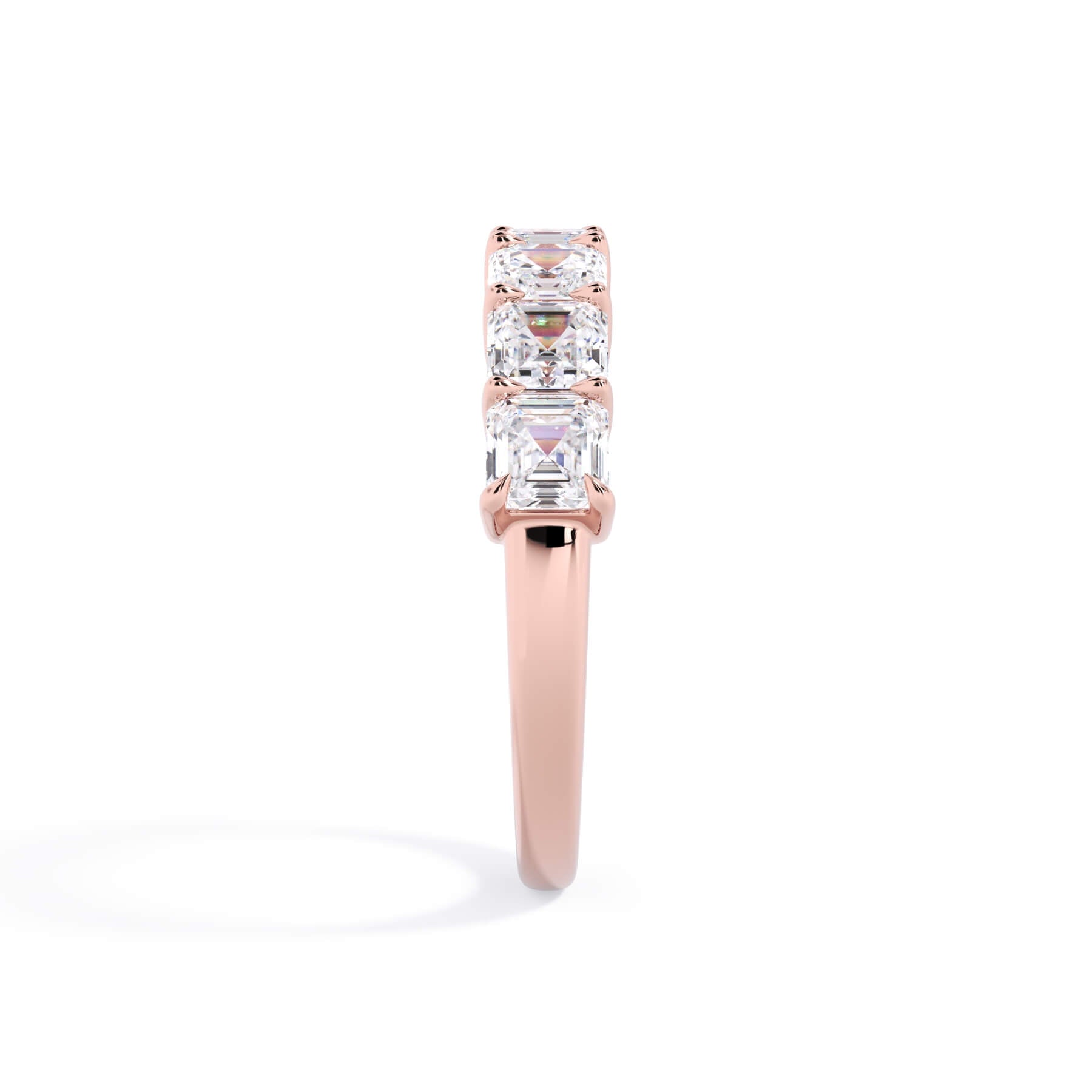 A picture of a seven stone diamond wedding ring with asscher cut diamonds that are shared prong set in rose gold on a white background with a side profile view.