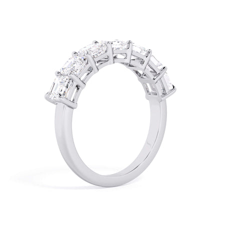 A picture of a seven stone diamond wedding ring with asscher cut diamonds that are shared prong set in white gold or platinum on a white background with a slightly angled, through the finger view.